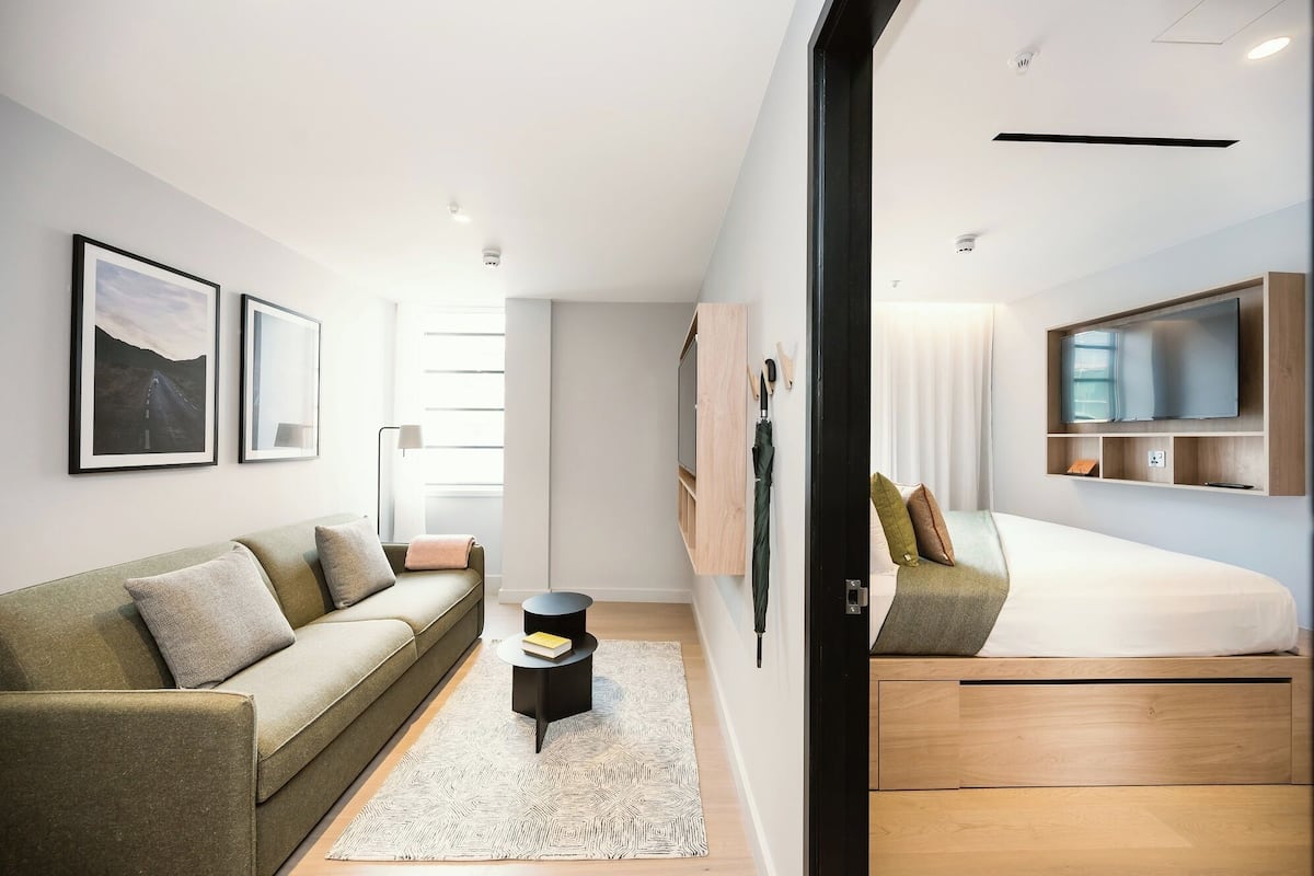 A modern bedroom with a bed, a sofa, a TV, and a desk.