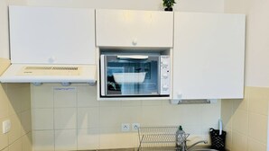 Une cuisine équipée d’un four à micro-ondes encastré, d’une cuisinière, d’un évier et d’une petite étagère située au-dessus du four à micro-ondes.