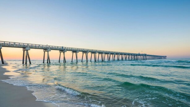 A pier extending into the water with a clear sky above.