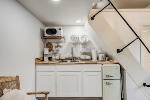 A compact kitchen with white cabinets, a microwave, a coffee maker, and a refrigerator. - Luxury Cottage Getaway

 (Stillwater)