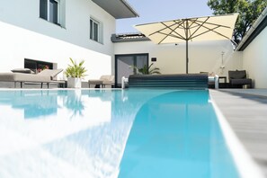 Una piscina al aire libre de temporada, sombrillas, tumbonas
