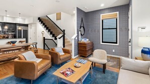 A modern living room with a wooden coffee table, leather sofas, and a staircase leading to the upper floor.
