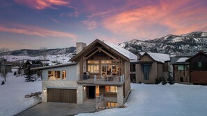 A modern house with a balcony, large windows, and a stone facade. - New + Contemporary + Neighborhood Gondola | Dala Horse Lodge (Steamboat Springs)