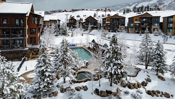 A snow-covered resort with multiple buildings, a central pool area, and surrounding trees. - New + Contemporary + Neighborhood Gondola | Dala Horse Lodge (Steamboat Springs)