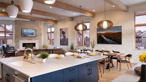 A modern kitchen with a large island, dining area, and a fireplace. - New + Contemporary + Neighborhood Gondola | Dala Horse Lodge (Steamboat Springs)
