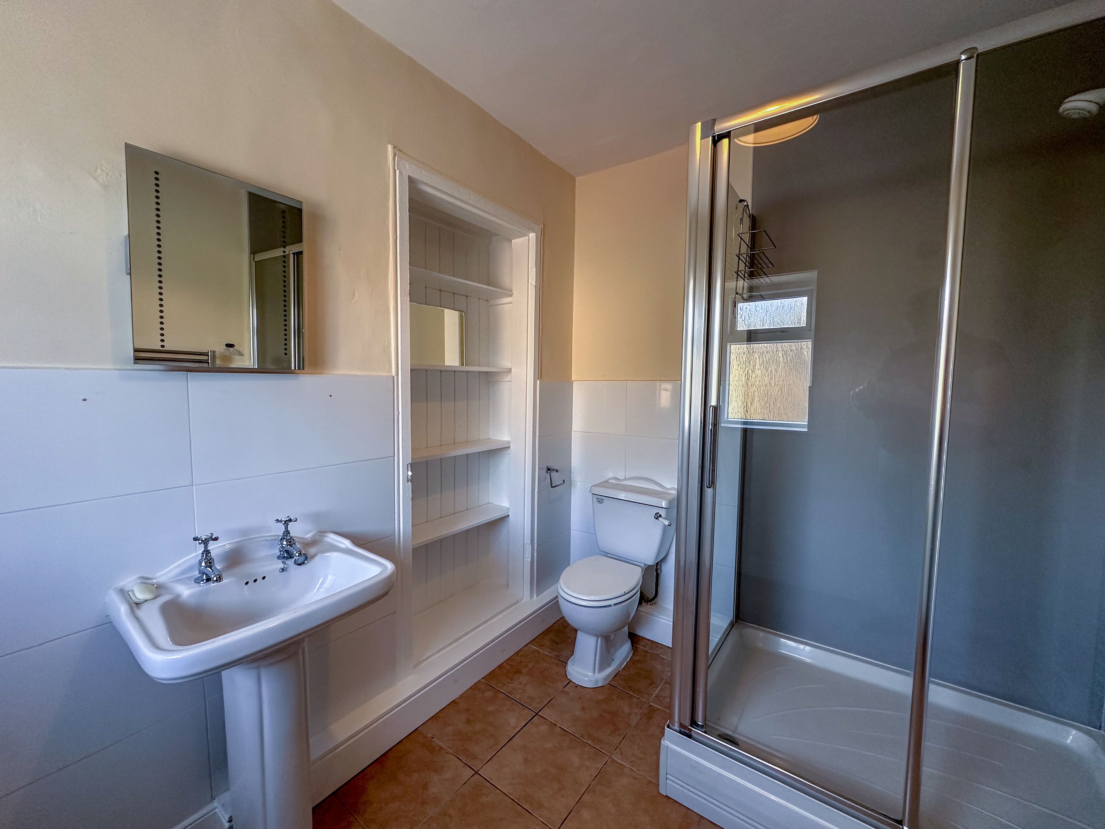A bathroom with a white sink, toilet, and glass-enclosed shower.