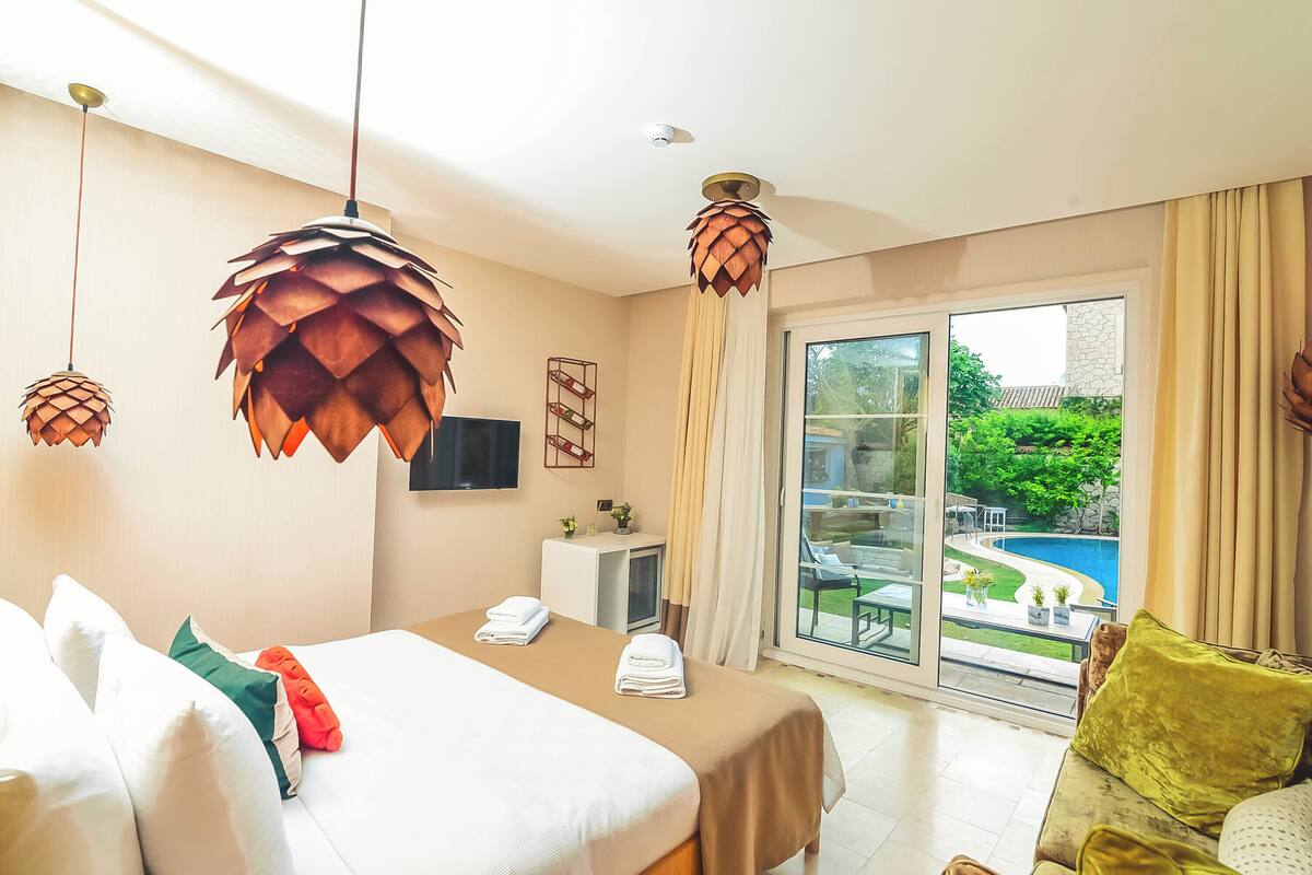 A hotel room with a bed, a desk, a TV, and a view of a swimming pool.