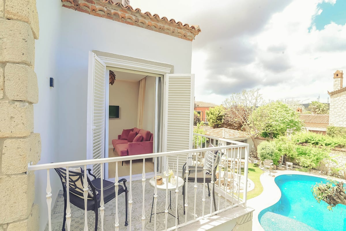 A balcony with a pool, a red chair, and a table.