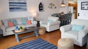 A living room with a sofa set, a coffee table, and a dining area with chairs and a table.