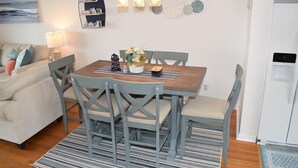 A dining area with a wooden table, four chairs, a decorative wall piece, and a water dispenser.