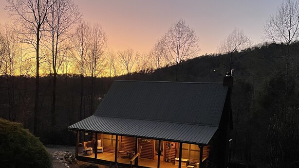Une cabane dotée d’une grande façade vitrée, d’un toit en pente et d’un chemin de pierre menant à l’entrée.
