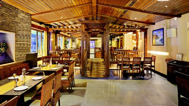 A spacious restaurant with high wooden ceilings, multiple dining tables, and chairs. - Hotel Twin Tulips HSR Layout (Bengaluru)