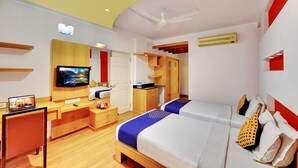 A modern hotel room with a bed, desk, TV, and a kitchenette. - Hotel Twin Tulips HSR Layout (Bengaluru)