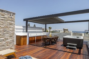 Enjoy breathtaking views of the city and sea from this rooftop terrace with a bar, hot tubs, and comfortable seating.