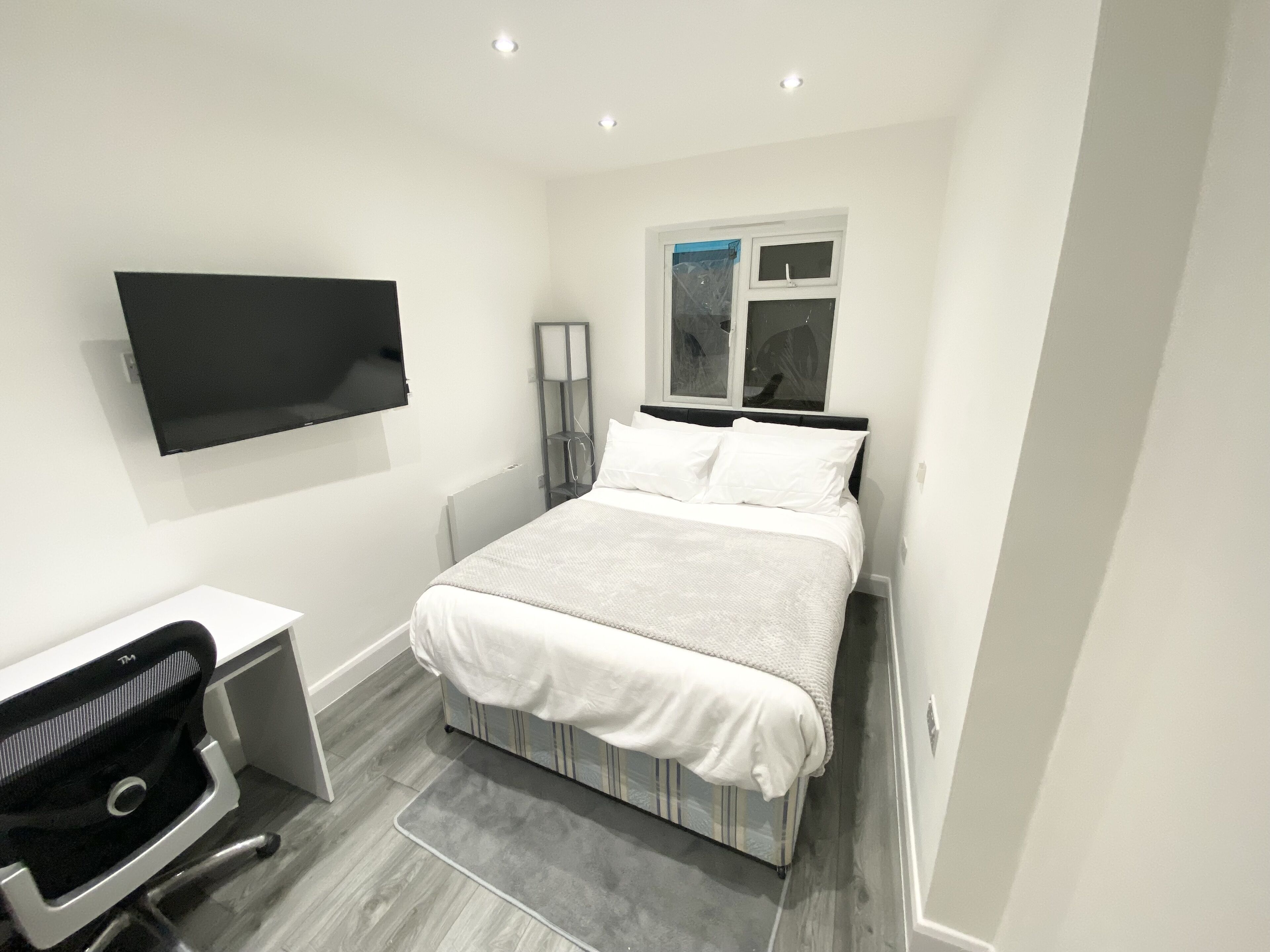 A modern bedroom with a bed, a desk, and a chair.