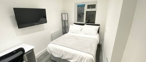 A modern bedroom with a bed, a desk, and a chair.