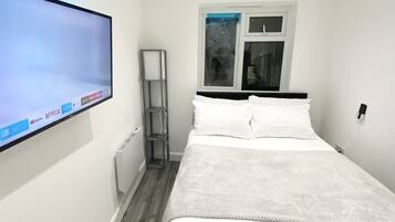 Et moderne soveværelse med seng, fjernsyn ophængt på væggen, et vindue med udsigt og en radiator.