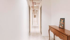 Un pasillo con un banco de madera y un cuadro en la pared.