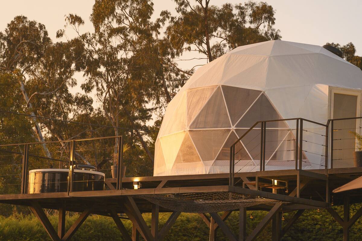 A geodesic dome structure with a balcony, a pool, and a seating area.