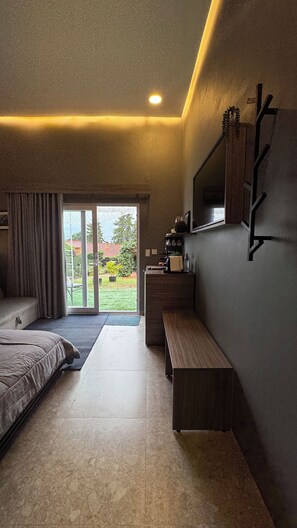 A modern bedroom with a bed, a bench, a desk, and a TV mounted on the wall. - Samaipata Glamping (Samaipata)