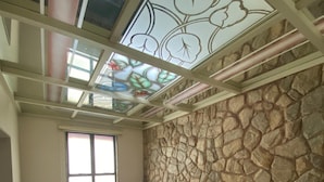 Un cuarto de spa con pared de piedra, una bañera grande y un tragaluz con motivos florales.