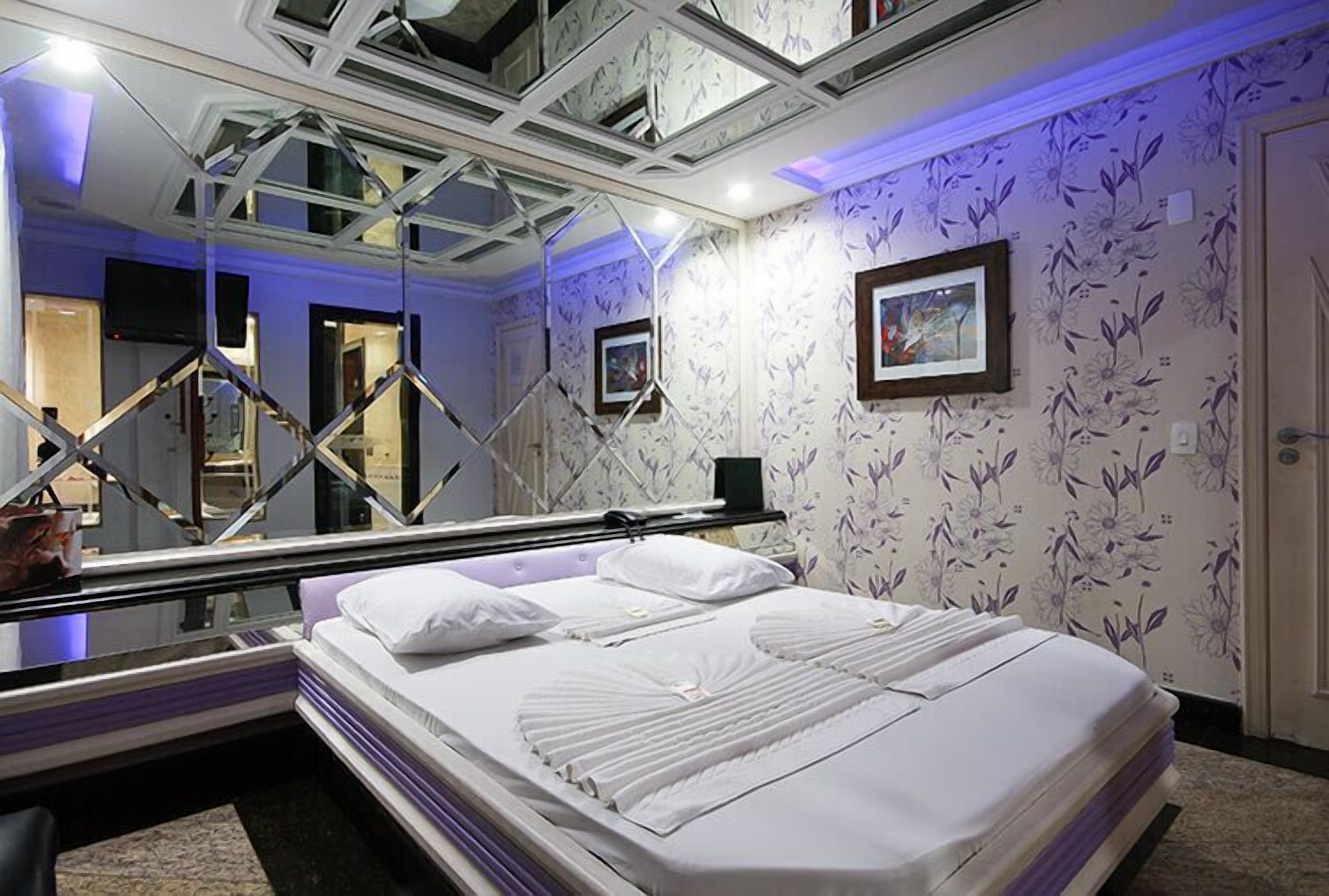 Una habitación de hotel con una cama, un espejo grande y un techo con diseño geométrico.