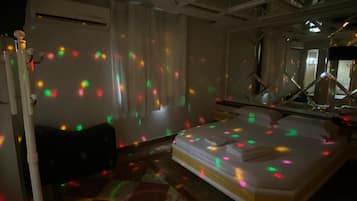 Ein Zimmer mit einem Bett, einer Stehlampe und Deckenleuchte.