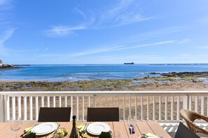 Mesa de madera preparada para dos personas, con vista a la playa y al océano.
