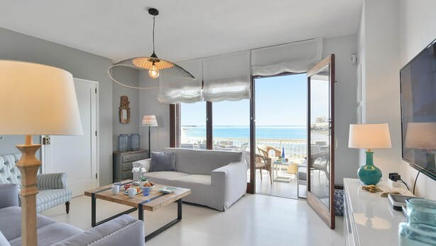 Een moderne woonkamer met een bank, salontafel en uitzicht op zee.