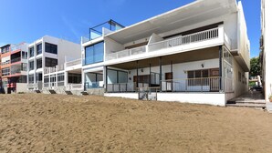 Een modern gebouw aan het strand, met meerdere balkons en grote ramen.