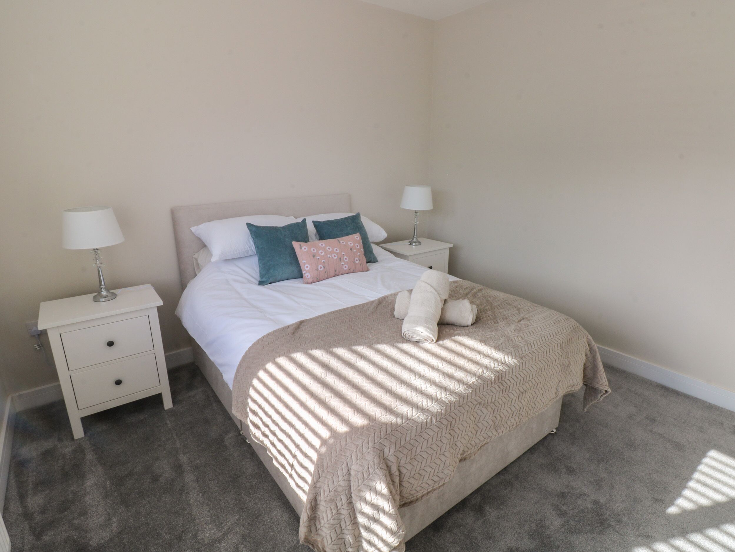 Une chambre à coucher avec un lit, deux tables de chevet et une commode.