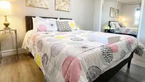 Un dormitorio con cama, mesitas de noche y obras de arte en las paredes.