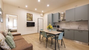 A modern kitchen with grey cabinets, a wooden dining table, and a sofa with patterned cushions. - Mercato Contemporary Apartment by Mmega (Florence)
