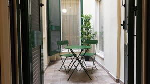 A narrow hallway with a green door, a window with a curtain, and a small table with chairs. - Mercato Contemporary Apartment by Mmega (Florence)