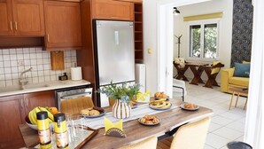 Eine moderne Küche mit Holzschränken, einem Edelstahlkühlschrank und einem Essbereich mit einem für das Frühstück gedeckten Tisch.