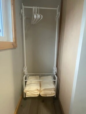 A narrow hallway with a white metal rack holding folded towels. - Tiny House on Farm (Wray)