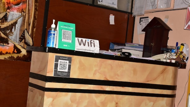 Una mesa de recepción con un cartel de Wifi, un código QR y un envase de gel para después del afeitado.