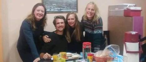 A group of people at a dining table with various food items and a coffee machine.