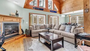 A cozy living room with a fireplace, a large sectional sofa, and a wooden ceiling with skylights. - Sunday River 5 Min!  Family / Group / Couples Retreat! (Newry)
