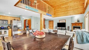 A spacious living area with a dark wooden dining table, a fireplace, and a television. - Sunday River 5 Min!  Family / Group / Couples Retreat! (Newry)