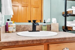 A bathroom with a white sink, a black faucet, and toiletries on the counter.