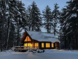 A cabin with a wooden exterior, large windows, and a porch area.
