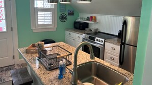 A kitchen with a granite countertop, stainless steel appliances, a sink, and pendant lights. - Large 1 bedroom condo in the historic area of Key West! (Key West)