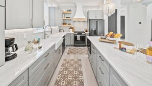 Una cucina moderna con isola centrale, elettrodomestici in acciaio inossidabile e un lampadario.