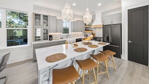 Una cucina moderna con isola in marmo, sgabelli in legno e frigorifero nero.