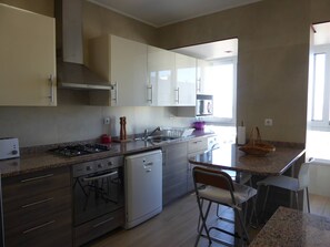A kitchen with a stove, oven, sink, and bar stools.