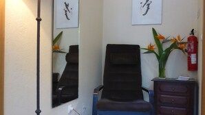 Une pièce comprenant un lampadaire, une chaise, une commode et deux œuvres d’art encadrées accrochées au mur.