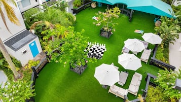 A rooftop garden with a chess table, outdoor seating, and a large umbrella.