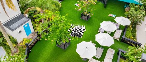 Un jardin sur le toit avec une table d’échecs, des sièges d’extérieur et un grand parasol.