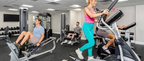 Ein Fitnessstudio mit Cardiogeräten, Gewichte und einer Spiegelwand.
